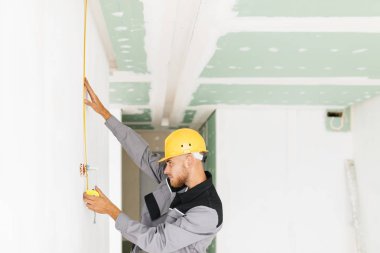 İş elbiseleri ve iş vakit ölçüm bandı kullanarak Sarı kask genç Oluşturucu