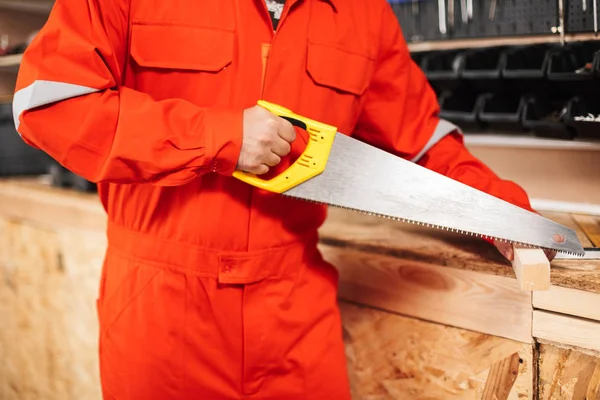 Close Builder Orange Work Clothes Sawing Wooden Plank Handsaw Workshop — Stock Photo, Image