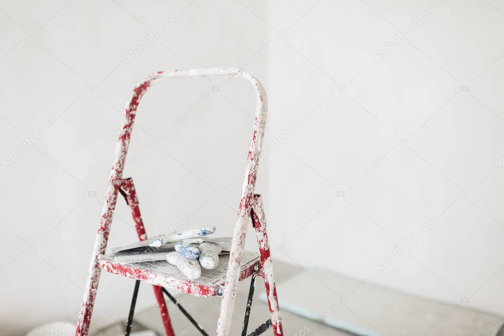 Close up ladder with putty knives over white background 