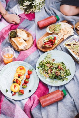 Güzel piknik ile çeşitli lezzetli yiyecekler ve güler yüzlü şişe üzerinde park piknik battaniyeye kadar kapatın 