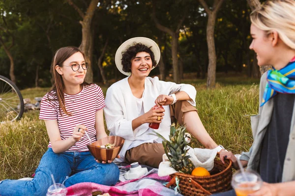 愉快的女孩坐在野餐毯愉快地谈论花时间在公园野餐 — 图库照片