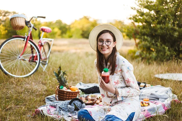 Leuk Lachende Meisje Brillen Hoed Zittend Picknickkleed Bedrijf Smoothie Fles — Stockfoto