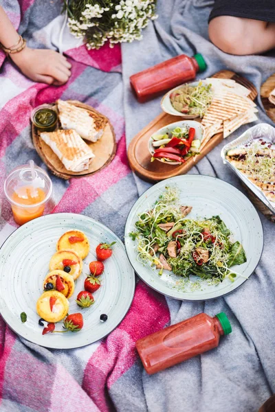 Güzel piknik ile çeşitli lezzetli yiyecekler ve güler yüzlü şişe üzerinde park piknik battaniyeye kadar kapatın 