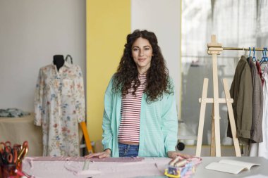 Genç güzel moda tasarımcısı mutlu bir şekilde fotoğraf dikiş atölyede çalışan arıyorsunuz 