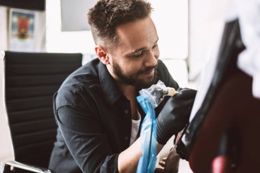 Profesyonel tattooer dövme makinesi modern Studio tarafından istemci el dövme yapıyor gülümseyen