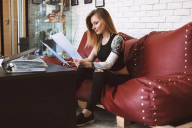 Dövmeli kız kanepe düşünceli izlerken yeni dövme skeçler modern tattoo Studio vakit oturan