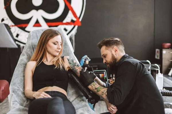 Profesyonel tattooer dövme dövme makinesi modern dövme Studio'yu kullanarak kız yandan yapıyor