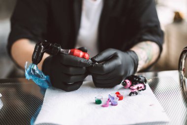 Tattooer siyah eldiven dövme makinesi modern tattoo Studio renkli mürekkepler ile çalışmaları için hazırlama kapatın