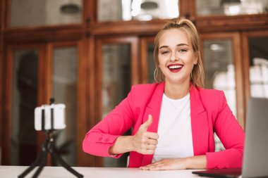 Güzel gülümseyen kız mutlu kamera seyir gösteren başparmak vlo için yeni video kayıt kadar pembe ceketli