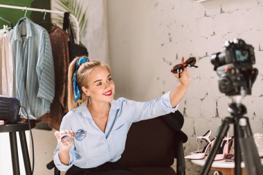 Mutlu bir şekilde kayıt yeni moda trendy güneş gözlüğü kamera vlog için video gösteren oldukça gülümseyen güzellik blogger