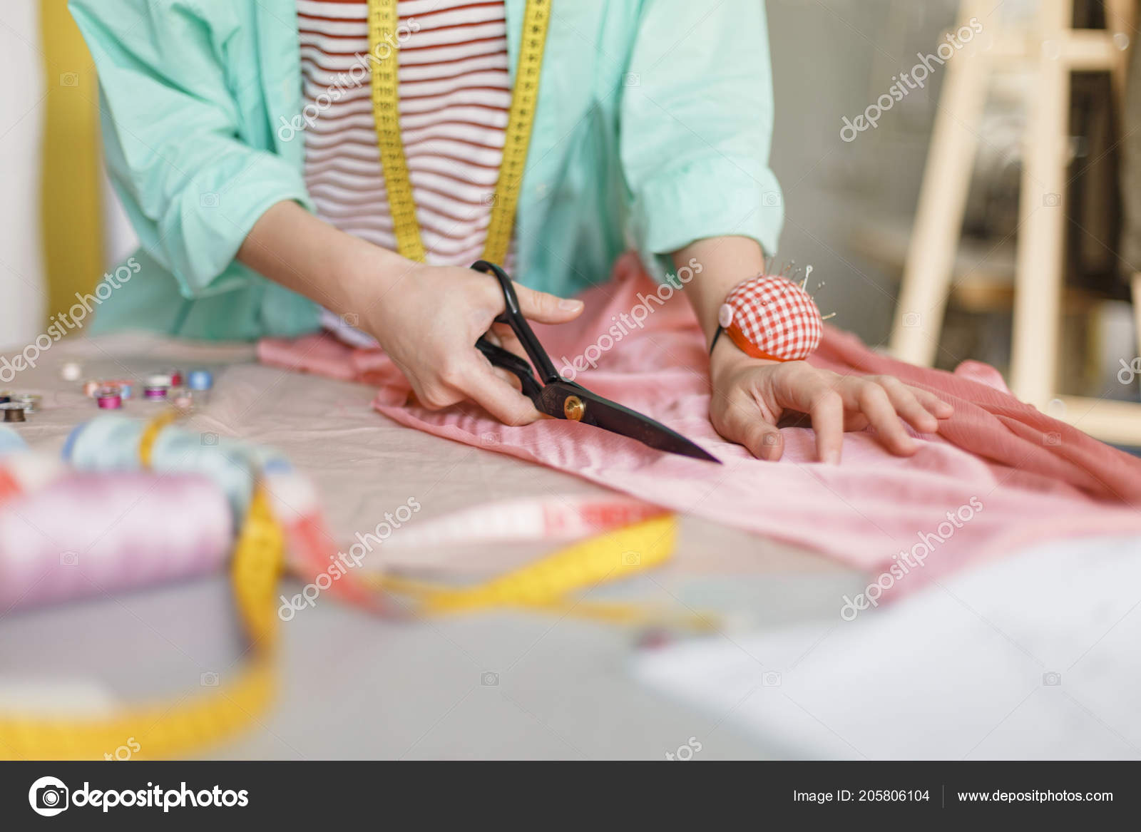 Tailor hand hold scissors cut fabric material for sewing. Closeup of work  process of clothes creation in workshop studio or professional atelier.  Garment industry and dressmaking occupation concept Stock Photo