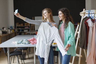 Mutlu müşteri yeni tutan el terzi modern dikiş Atölyesi cep telefonu ön kamera ile fotoğraf çekmek askı elbise çizgili