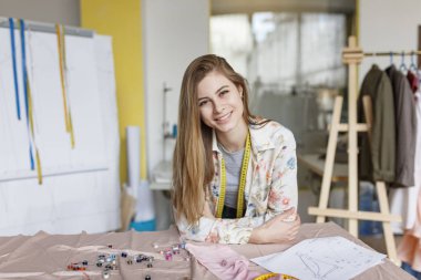 Sevinçle kamera modern dikiş Atölyesi boynundan kasette ölçme ile seyir masada eğilerek neşeli kız terzi