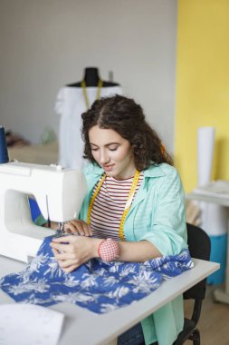 Renkli gömlek ve çizgili tişört sersem dikiş makinesi modern dikiş atölyesinde çalışan oldukça gülümseyerek terzi