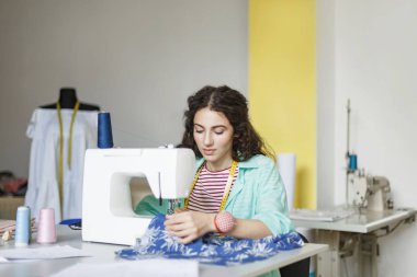 Renkli gömlek ve çizgili tişört güzel terzi dikiş makinesi modern dikiş Atölyesi kumaş ile çalışma kullanarak