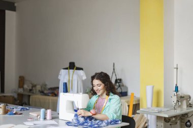 Mutlu bir şekilde kullanarak dikiş makinesi modern dikiş Atölyesi kumaş ile çalışma güzel gülümseyerek terzi
