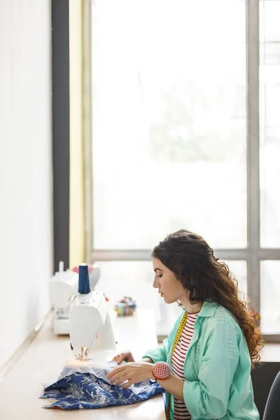 Молодая Швея Красочной Рубашке Задумчиво Использует Швейную Машинку Большим Окном — стоковое фото