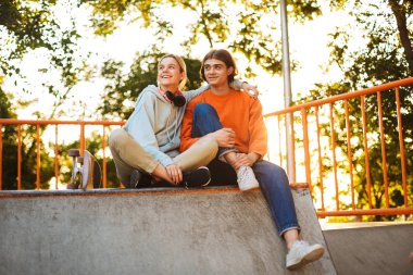 Erkek ve kız mutlu seyir bir kenara harcama zaman birlikte skatepark gülümseyen genç 