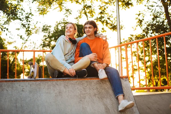 年轻的微笑的男孩和女孩高兴地看着一边花时间在 Skatepark — 图库照片