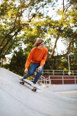 Kaykay ve modern skatepark zaman harcama stunts pratik portakal kazak genç adam