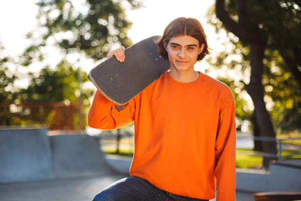 Young Smiling Skater Orange Pullover Happily Looking Camera Holding Skateboard — Stock Photo, Image