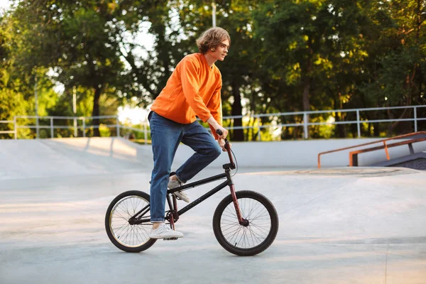Młody Człowiek Pomarańczowy Sweter Dżinsy Jazda Rowerowa Nowoczesny Skatepark — Zdjęcie stockowe