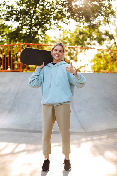 Όμορφο Κορίτσι Χαμογελά Hoodie Κρατώντας Skateboard Στον Ώμο Ευχαρίστως Βλέπουν — Φωτογραφία Αρχείου