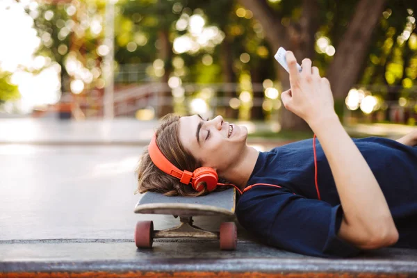 Retrato Chico Joven Con Auriculares Naranjas Acostado Monopatín Felizmente Usando —  Fotos de Stock