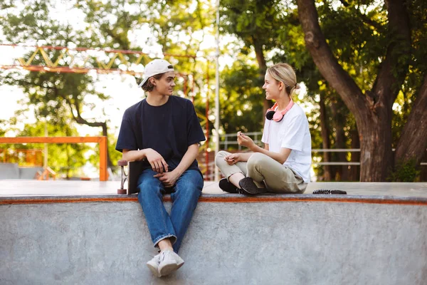 漂亮的女孩和年轻人愉快地谈论花时间在一起在现代 Skatepark — 图库照片