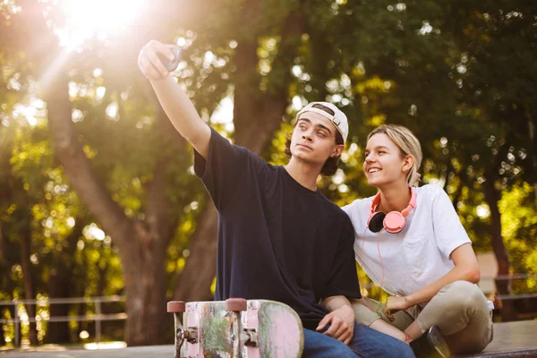 Chica Sonriente Con Auriculares Chico Joven Con Monopatín Feliz Tomar —  Fotos de Stock