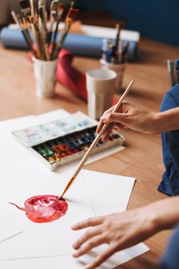 Kat tarafından renkli suluboya boya araçları kağıdına evde çizim oturan ressam kapatın