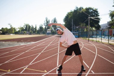 Düşünceli bir yana Stadyumu treadmill germe seyir şapkalı genç sportif adam