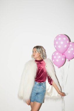 Güzel kız beyaz kürk ceket ve kadife bluz sersem bir kenara pembe balonlar beyaz arka plan üzerinde elinde tutan arıyorsunuz