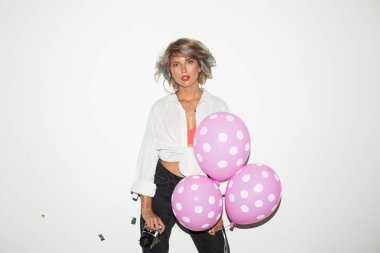 Güzel kız beyaz gömlekli sersem kamera tutarak retro kamera ve pembe balon elinde beyaz arka plan üzerinde seyir