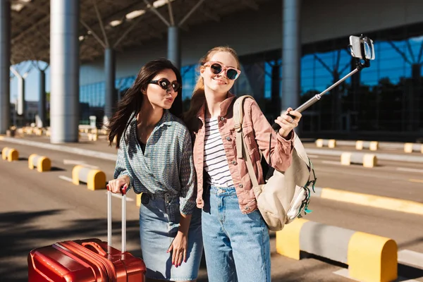 Две Симпатичные Девушки Солнечных Очках Радостно Фотографируют Мобильный Телефон Вместе — стоковое фото
