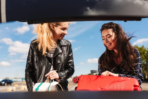 Twee Vrolijke Meisjes Gelukkig Vouwen Koffers Kofferbak Van Zwarte Auto — Stockfoto