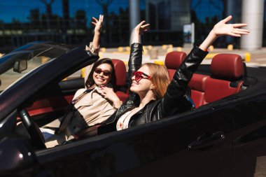 İki neşeli kız sevinçle harcama zaman birlikte cabriolet şehir sokaklarında açık araba