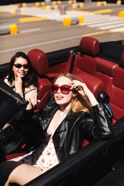 Sersem kamera sürüş cabriolet araba gülümseyen arkadaşıyla şehir sokaklarını açık seyir güneş gözlüğü güzel kız