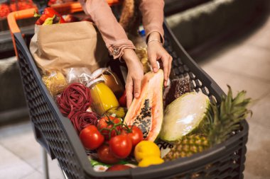 Papaya arabası taze ürünler ve tam modern süpermarkette holding kadın eller yukarı kapatın