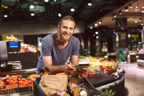 Jonge Vrolijke Kerel Leunend Trolley Koffer Vol Producten Gelukkig Kijken — Stockfoto