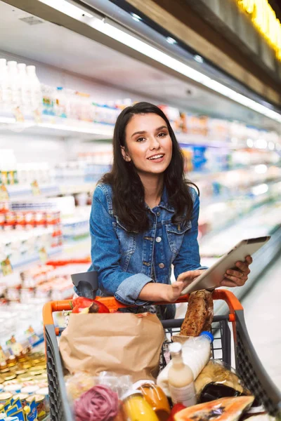 Ładna Dziewczyna Kurtka Dżinsowa Wózkiem Pełen Produktów Które Szczęśliwie Patrząc — Zdjęcie stockowe