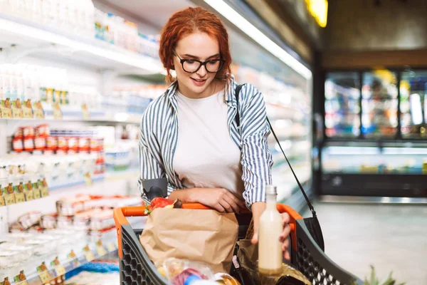 Söt Tjej Glasögon Och Randig Skjorta Med Kundvagn Full Produkter — Stockfoto