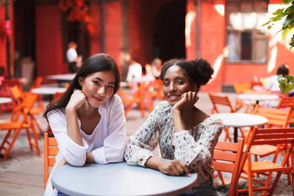 两个美丽的微笑的女孩靠在手朦胧地看着相机花时间一起在咖啡馆庭院 — 图库照片