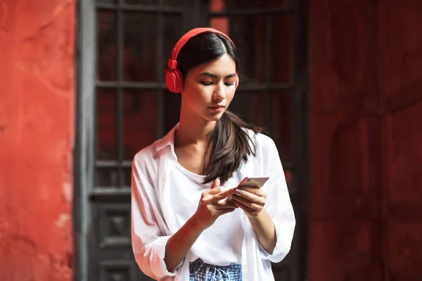 Wanita Muda Dengan Kemeja Putih Dan Headphone Merah Memikirkan Usinag — Stok Foto