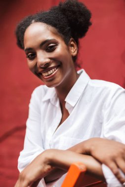 Beyaz gömlekli mutlu kamera açık seyir siyah kıvırcık saçlı güzel gülümseyen Afrikalı kız portresi