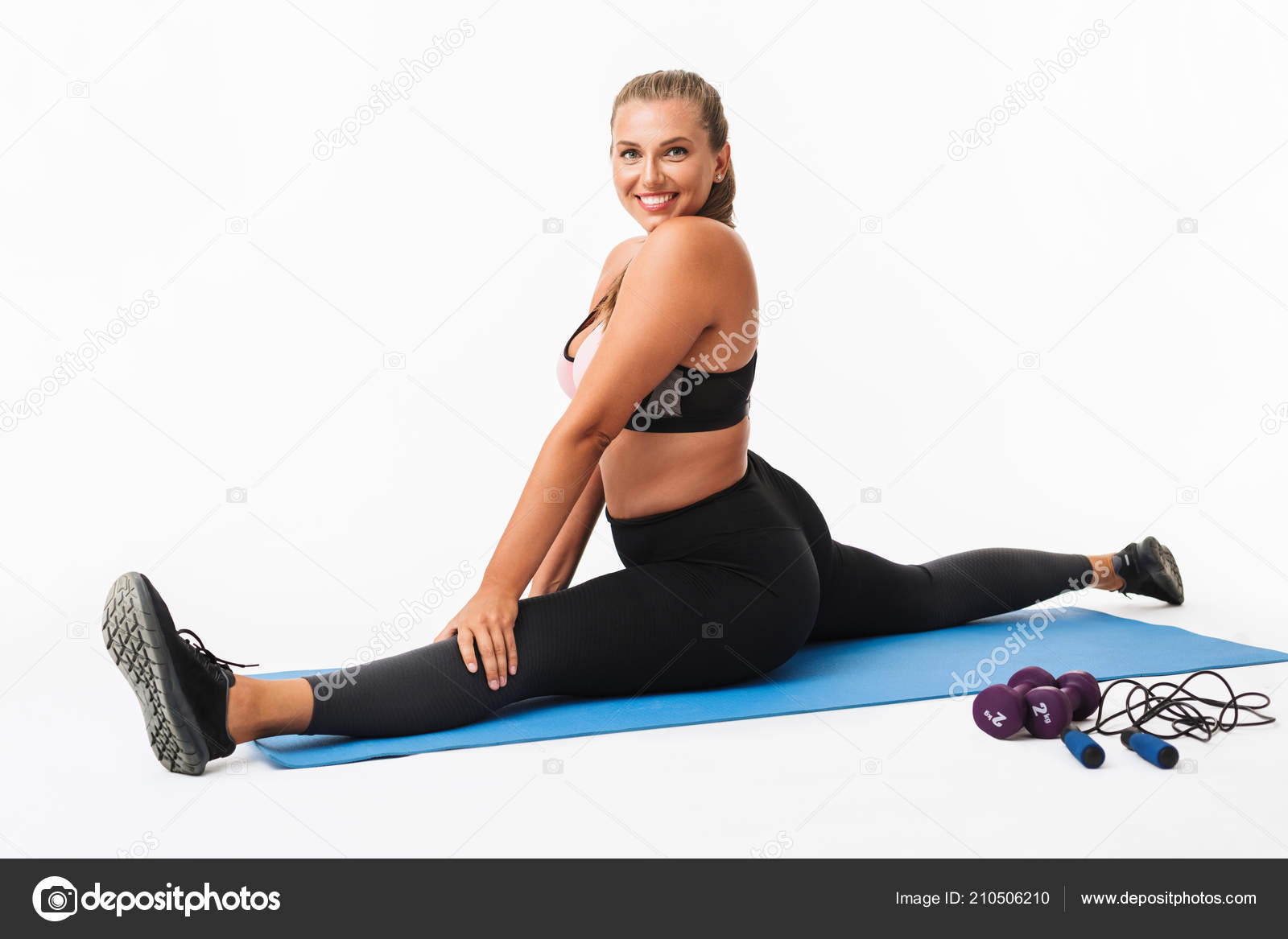 Young beautiful plus size woman in pink sporty top and leggings sitting on  orange yoga mat dreamily looking aside while spending time in park Stock  Photo
