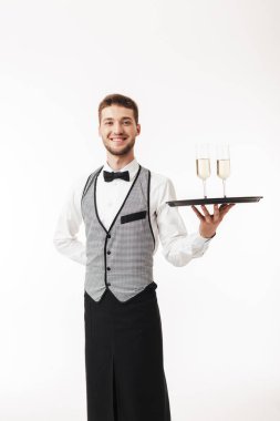 Mutlu bir şekilde kamera tutarak tepsi gözlük ile beyaz arka plan üzerinde seyir üniformalı genç neşeli garson