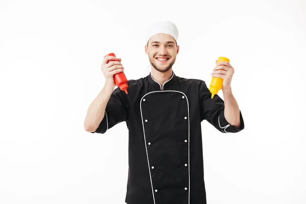 Joven Chef Masculino Alegre Uniforme Negro Sosteniendo Botellas Mostaza Ketchup — Foto de Stock