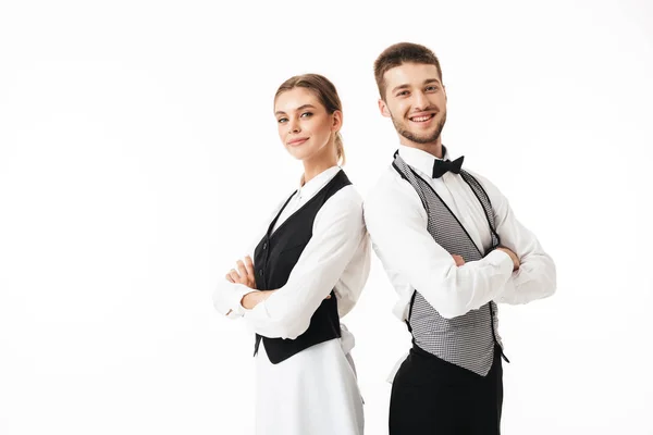Genç garson ve beyaz gömlek ve yelek sstanding sırt sırta güzel garson gülümseyerek mutlu bir şekilde kamera seyir silah ile beyaz arka plan üzerinde katlanmış