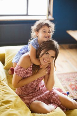 Siyah kıvırcık saçlı sarılmakla neşeli bebek kız anne mutlu kamera birlikte kanepede evde vakit arıyorsunuz 